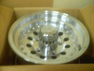 1989 Ford Bronco - Aluminum wheel with a polished finish and a center cap, shown inside a cardboard box.