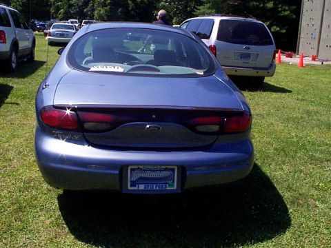 1999 Ford Taurus - Rear view of a blue 1999 Ford Taurus sedan parked on a grassy field.