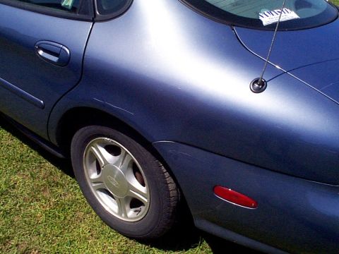 1999 Ford Taurus - Rear quarter panel and wheel of a blue 1999 Ford Taurus SE.