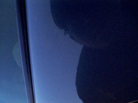 1999 Ford Taurus - A close-up shot focuses on the reflective surface of a dark blue car door, showing distorted reflections.