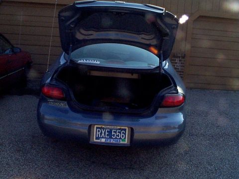 1999 Ford Taurus - The rear of a dark blue 1999 Ford Taurus is shown with its trunk open, revealing the interior space.