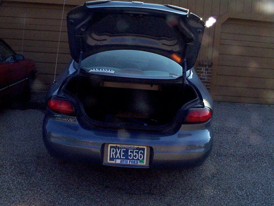Rear view of a dark blue 1999 Ford Taurus with open trunk and license plate RXE 556