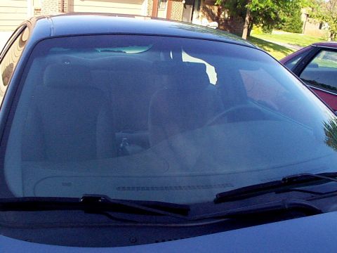1999 Ford Taurus - The dashboard and windshield of a blue 1999 Ford Taurus are visible, with another vehicle parked nearby.