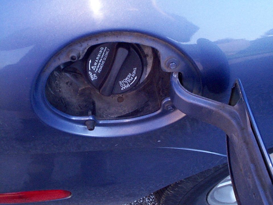 Blue car fuel door with warning text on cap