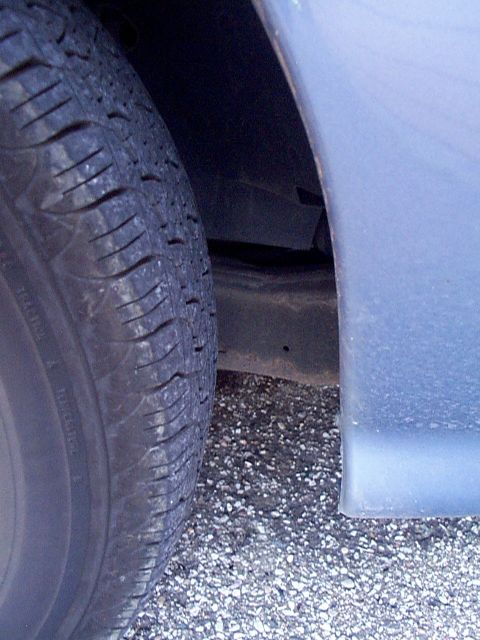 1999 Ford Taurus - A close-up view of a vehicle's tire and the lower part of its body panel.
