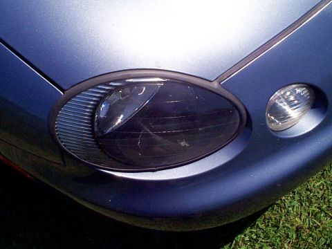1999 Ford Taurus - Close-up of a blue car's front corner, showing a headlight and part of the fender.