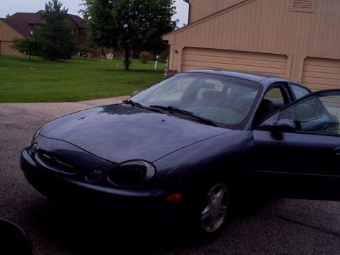 1999 Ford Taurus - Dark blue 1999 Ford Taurus SE parked in front of a house with the driver's door ajar.