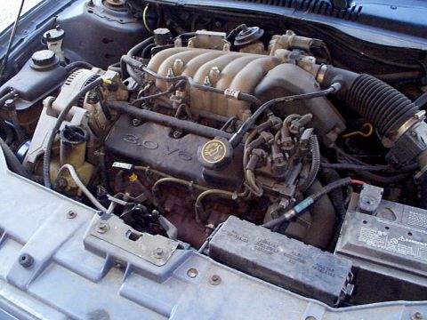 1999 Ford Taurus - The engine bay of a 1999 Ford Taurus is visible, the 3.0 V6 engine and associated components.