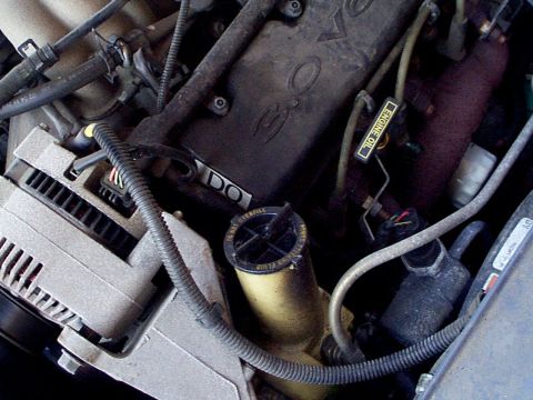 1999 Ford Taurus - Close-up of an engine bay, an alternator and a yellow fluid reservoir.