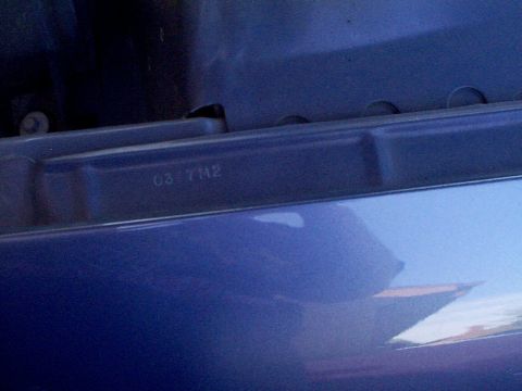 1999 Ford Taurus - A close-up view shows stamped numbers on a blue car part, possibly a VIN or manufacturing code.