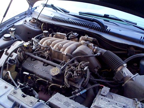1999 Ford Taurus - The engine bay of a 1999 Ford Taurus is visible with the hood raised.