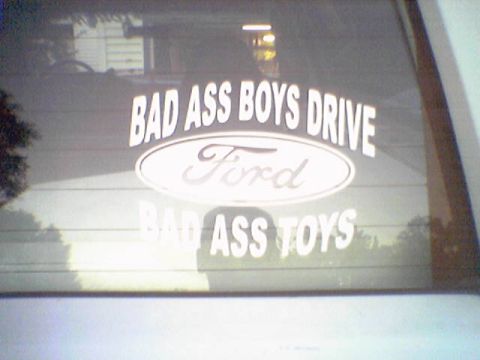1993 Ford Bronco - A sticker on the rear window of a vehicle displays the Ford logo and text about 'bad ass boys' and 'bad ass toys'.
