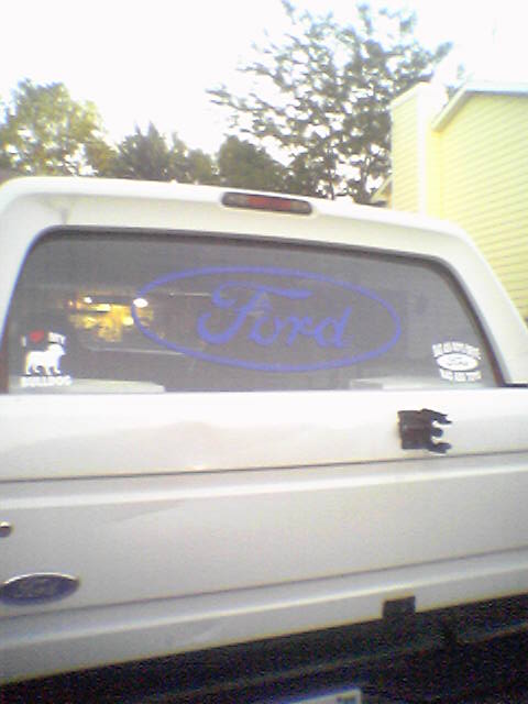 1993 Ford Bronco - Rear view of a white 1993 Ford Bronco, a prominent blue Ford oval decal on the window.