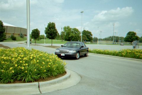 1998 Ford Crown Victoria - A dark 1998 Ford Crown Victoria is seen from a 3q-front angle on a paved road.