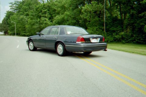 1998 Ford Crown Victoria - This Ford Crown Victoria is seen from the rear quarter as it drives down a two-lane road.