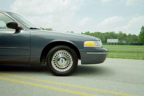 1998 Ford Crown Victoria - A 1998 Ford Crown Victoria is shown from the front three-quarter angle, highlighting its dark blue exterior.
