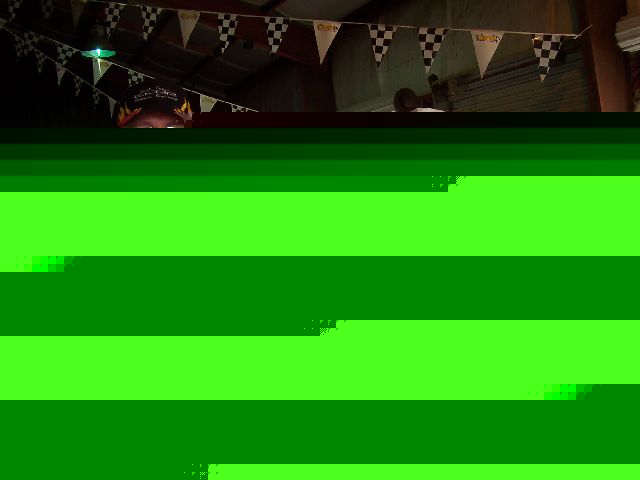 Checkerboard and triangular racing flags hang from a ceiling, with a person's head visible below