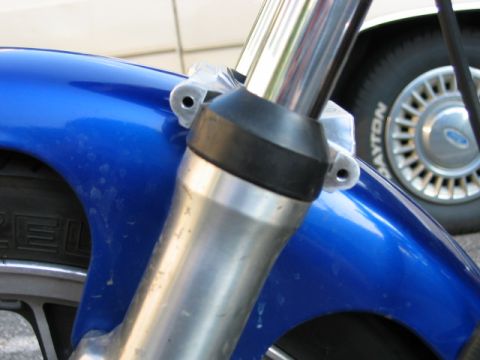 1985 Ford Crown Victoria LTD - A blue motorcycle fender and chrome fork are visible, with a car wheel in the background.