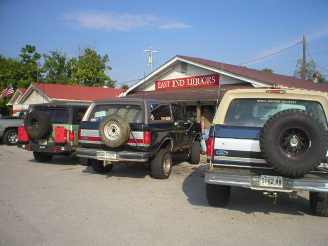 Three lifted Ford Broncos parked at East End Liquors storefront, rear view
