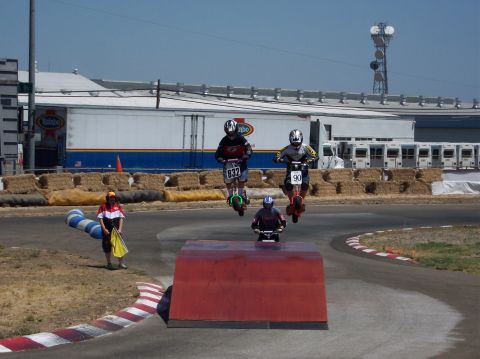 1990 Ford Bronco - A group of scooters are captured mid-air as they jump over a ramp during a race event.