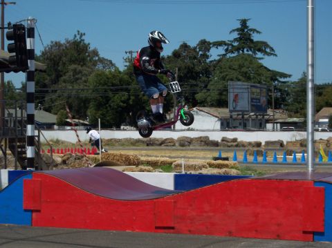 1990 Ford Bronco - A rider performs a jump on a scooter during an event, with a traffic light and spectators in the background.