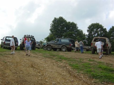 1995 Ford Bronco - Group of lifted 4x4 trucks and SUVs, including a dark green full-size Ford Bronco on mud-terrain tires and a tan Bronco with a spare tire o…