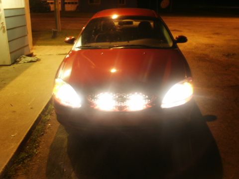2000 Ford Taurus - Red 2000 Ford Taurus sedan parked at night with its lights illuminated.