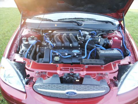2000 Ford Taurus - The engine bay of a red Ford Taurus is visible with the hood open, highlighting the Duratec V6 engine.