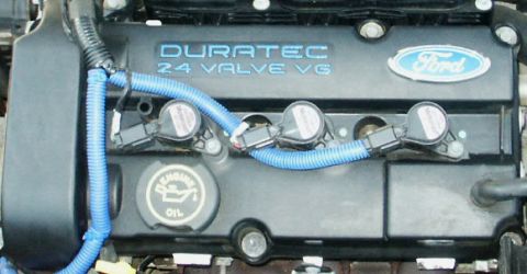 2000 Ford Taurus - Close-up of a Ford engine cover, showing the Duratec 24 Valve V6 designation and spark plug coils.