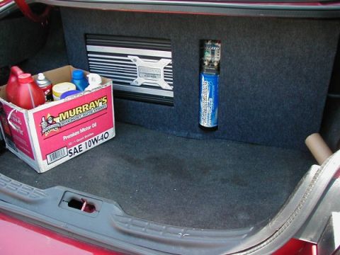 1997 Ford Taurus - The trunk of a car contains a box of oil, an amplifier, and a blue canister, with no visible year identification.