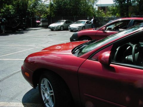 1997 Ford Taurus - A red 1997 Ford Taurus is parked in a lot with other vehicles visible.
