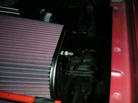 1994 Ford Bronco - Red pleated cone-style air filter with a black rubber end cap installed in a dark engine bay, photographed against the red painted inner fe…