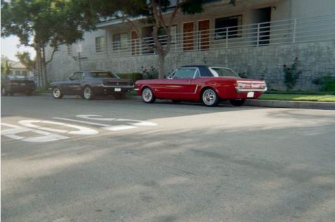 1968 Ford Mustang - Two classic Ford Mustangs are parked on a residential street in front of an apartment building.