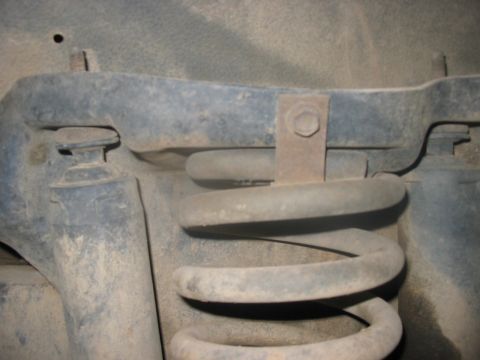 1988 Ford Bronco - Vehicle suspension coil spring and metal bracket detail.