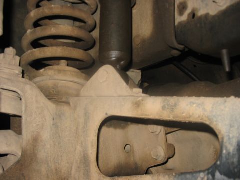 1988 Ford Bronco - Close-up view of the front suspension shock absorber and coil spring assembly, showing mechanical components.