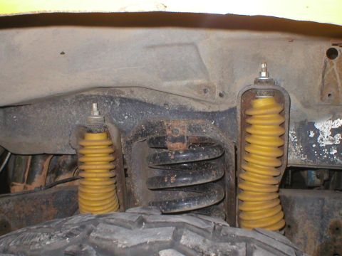 1978 Ford Bronco - Close-up of the front suspension system, showing yellow shock absorbers and coil springs.