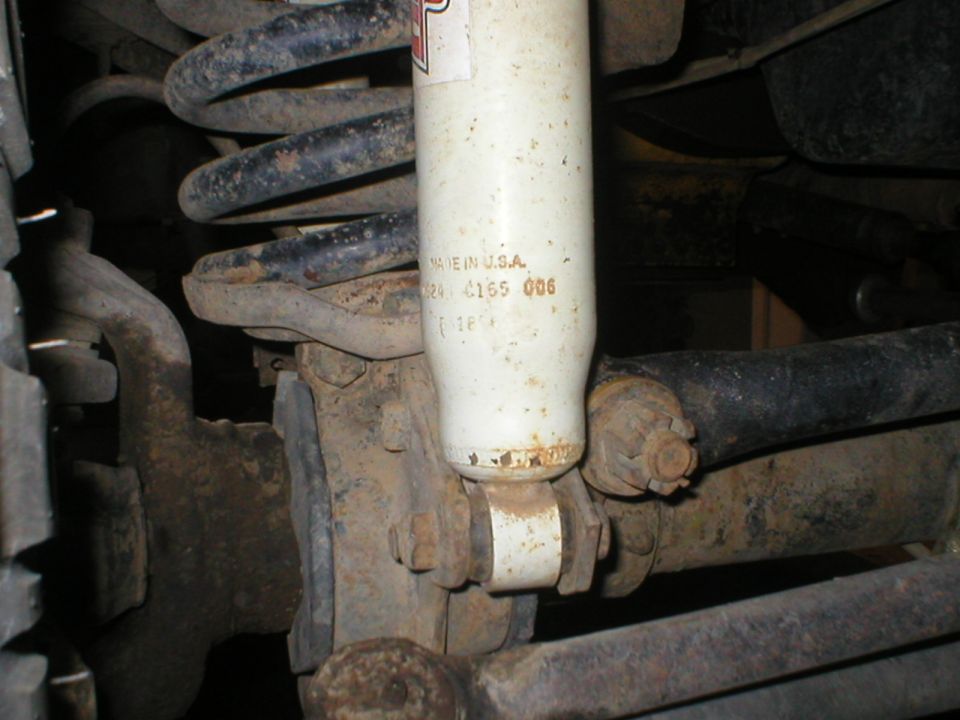 White shock absorber with visible text and suspension parts