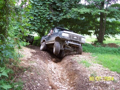 1995 Ford Bronco - Truck driving off-road through a ditch with another vehicle in the background.