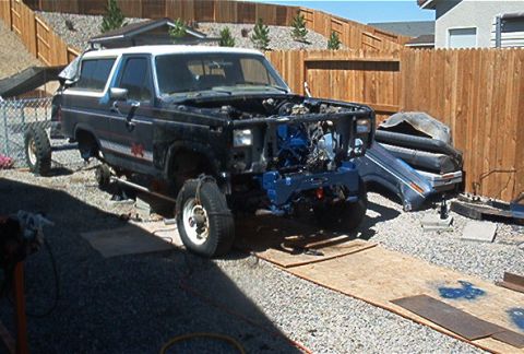 1986 Ford Bronco - This vehicle is undergoing repairs with its front end disassembled and engine visible.