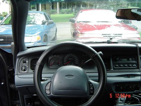 1999 Ford Crown Victoria - The interior of a sedan is shown, with two other vehicles parked outside.