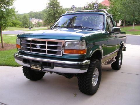 1996 Ford Bronco - This lifted 1996 Ford Bronco is parked on a suburban driveway with a wooded background.