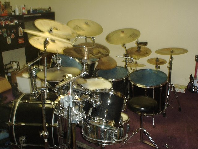 Large drum kit with cymbals and black drums in a carpeted room