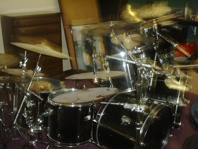 Black drum kit with cymbals and toms set up in a room