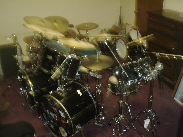 Black drum kit with many cymbals in a carpeted room