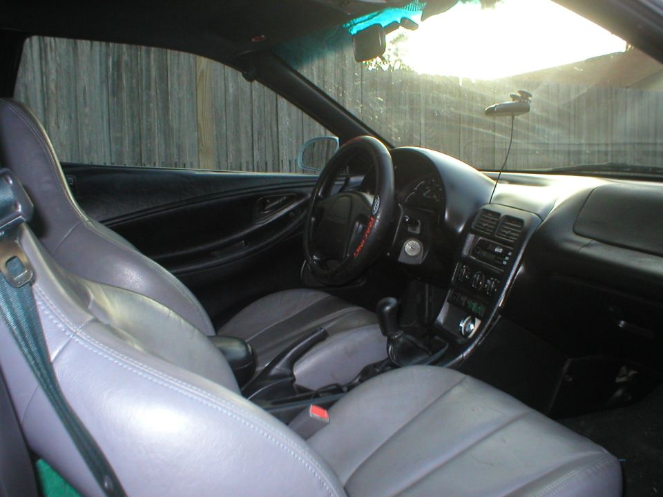 Interior of a Ford Probe with gray leather seats, manual shifter, and Ford Racing steering wheel cover