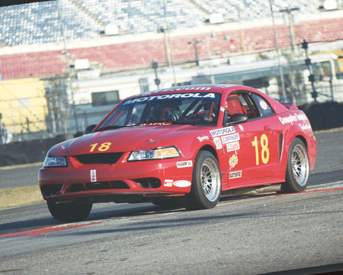 red race car with number 18 on door and hood, driving on a track
