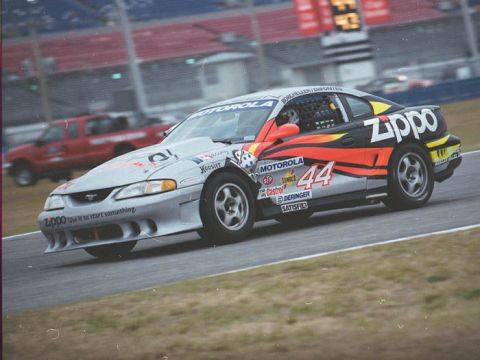 1995 Ford Mustang - A race car with Zippo and Motorola sponsorship competes on a track.