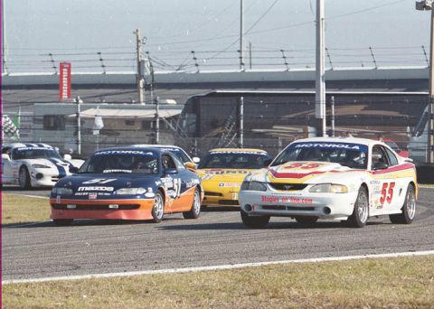 1995 Ford Mustang - Multiple race cars, including a 1995 Ford Mustang, compete on a track.