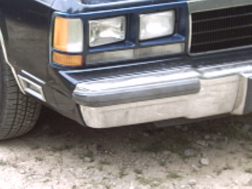 Front corner of a dark blue car, showing headlights, turn signal, grille, and bumper