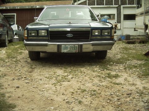 1990 Ford Crown Victoria LTD - A 1988 Ford Crown Victoria is seen from the front in a gravel lot with a garage in the background.